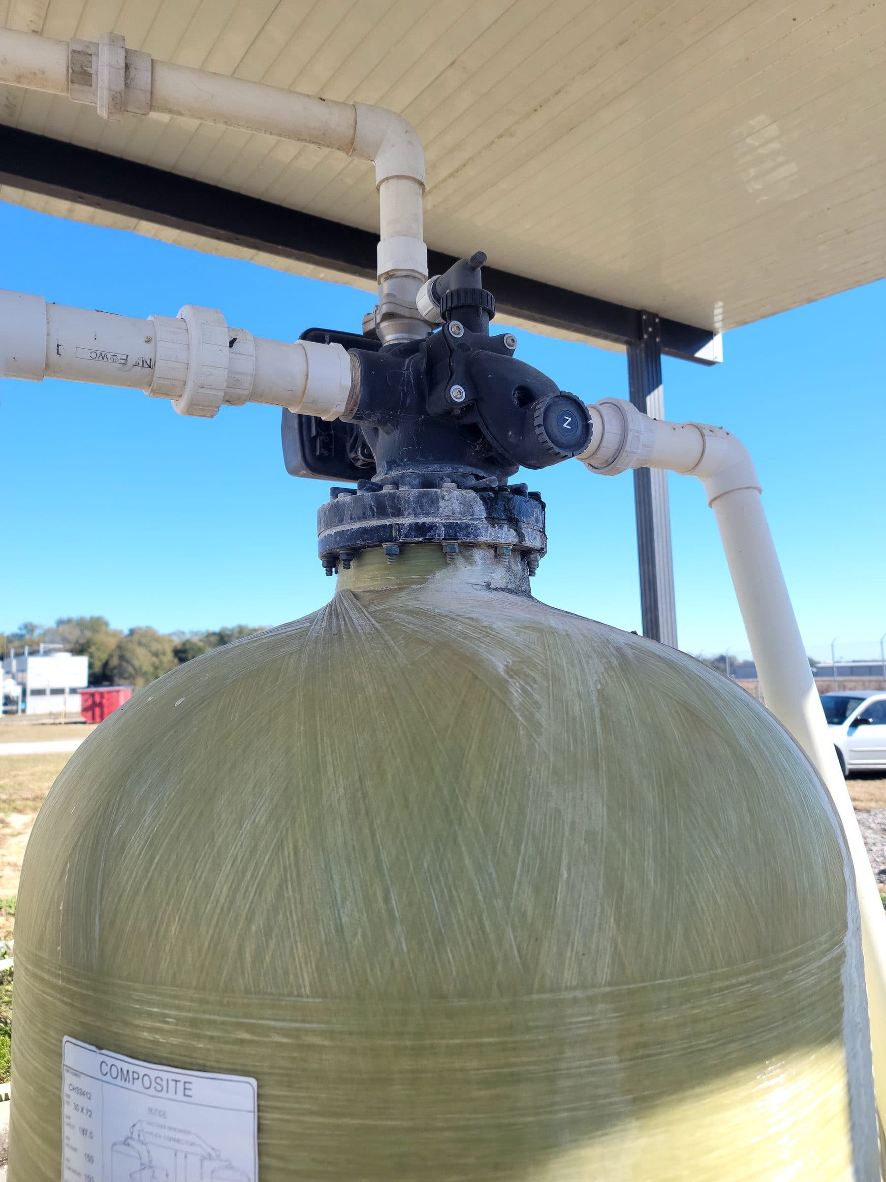 Close-up of a fiberglass mineral tank control valve on a commercial install