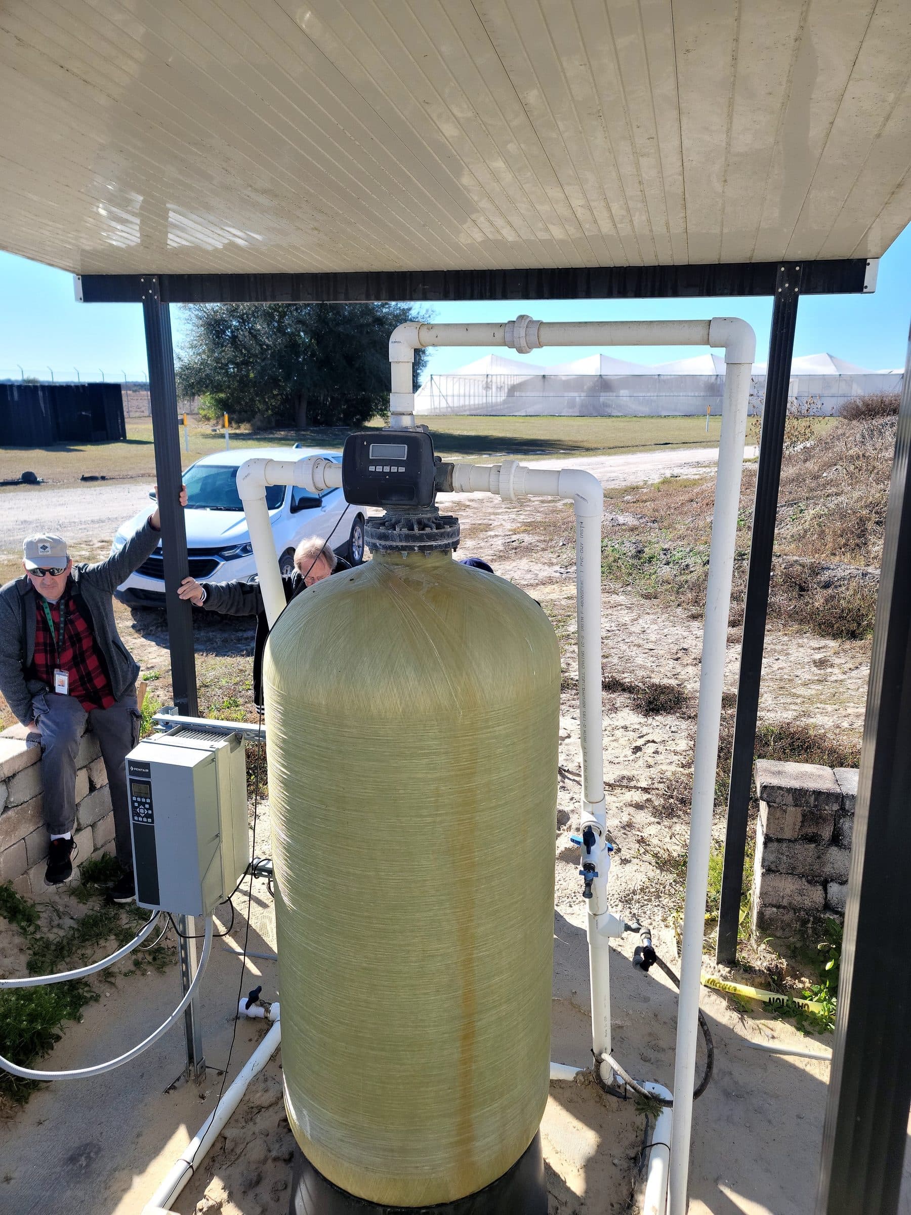 Technicians installing a fiberglass mineral tank at a commercial property
