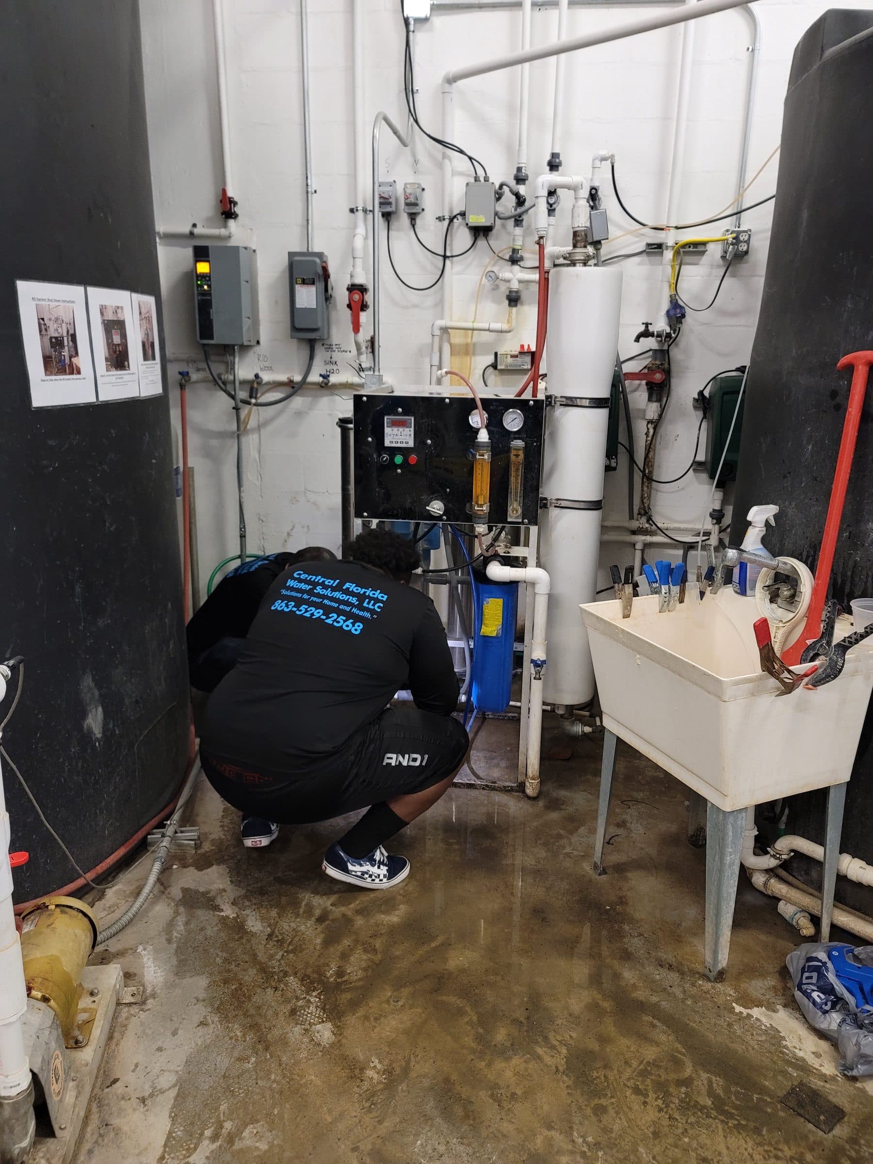 Central Florida Water Solutions technician servicing a commercial RO skid, gauges and membrane housings visible
