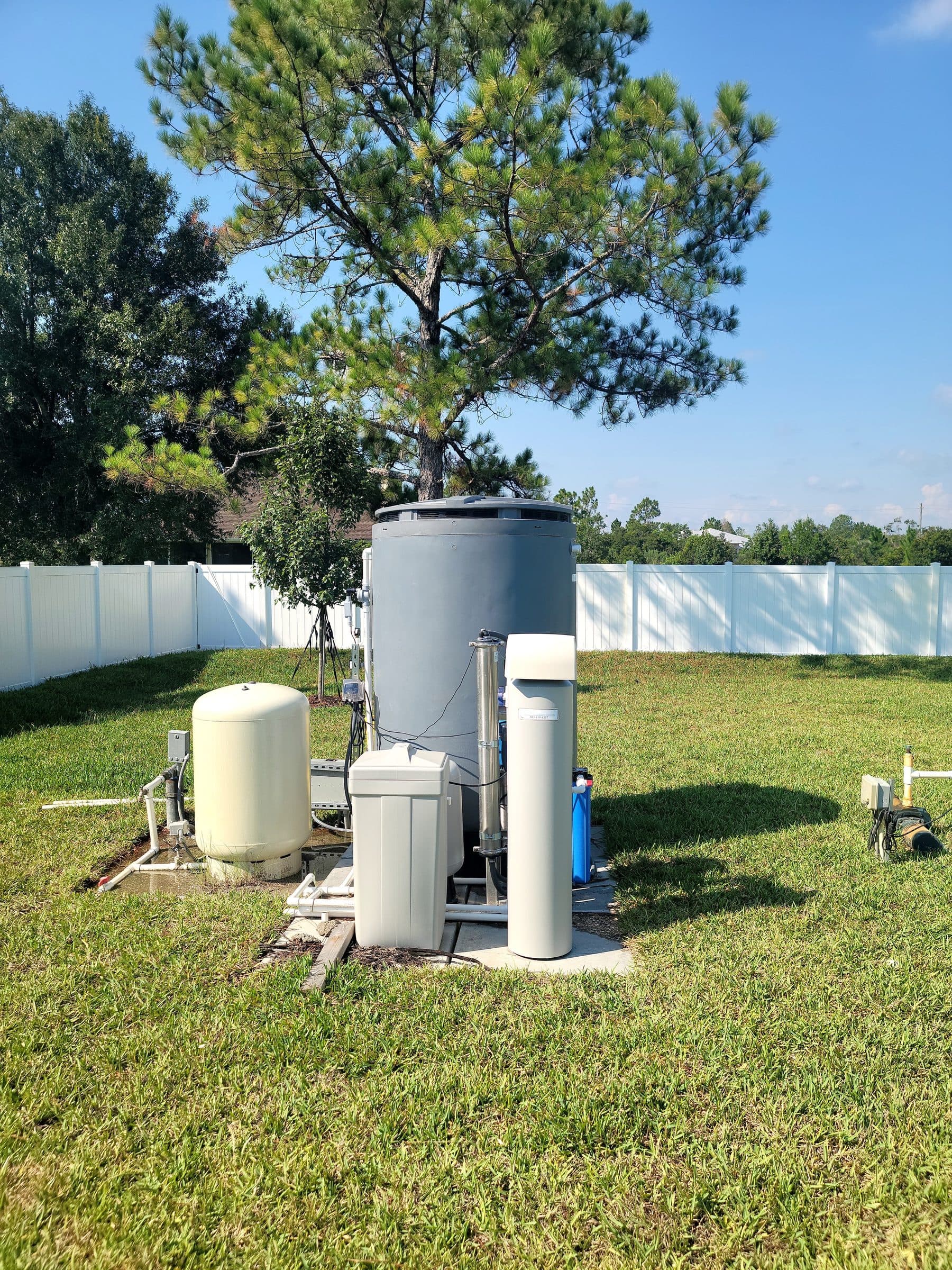 Twin softener tanks installed beneath a shaded side yard